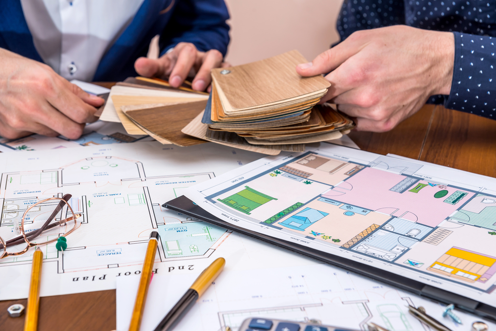 Contractor reviewing flooring samples on a table with blueprints or plans.